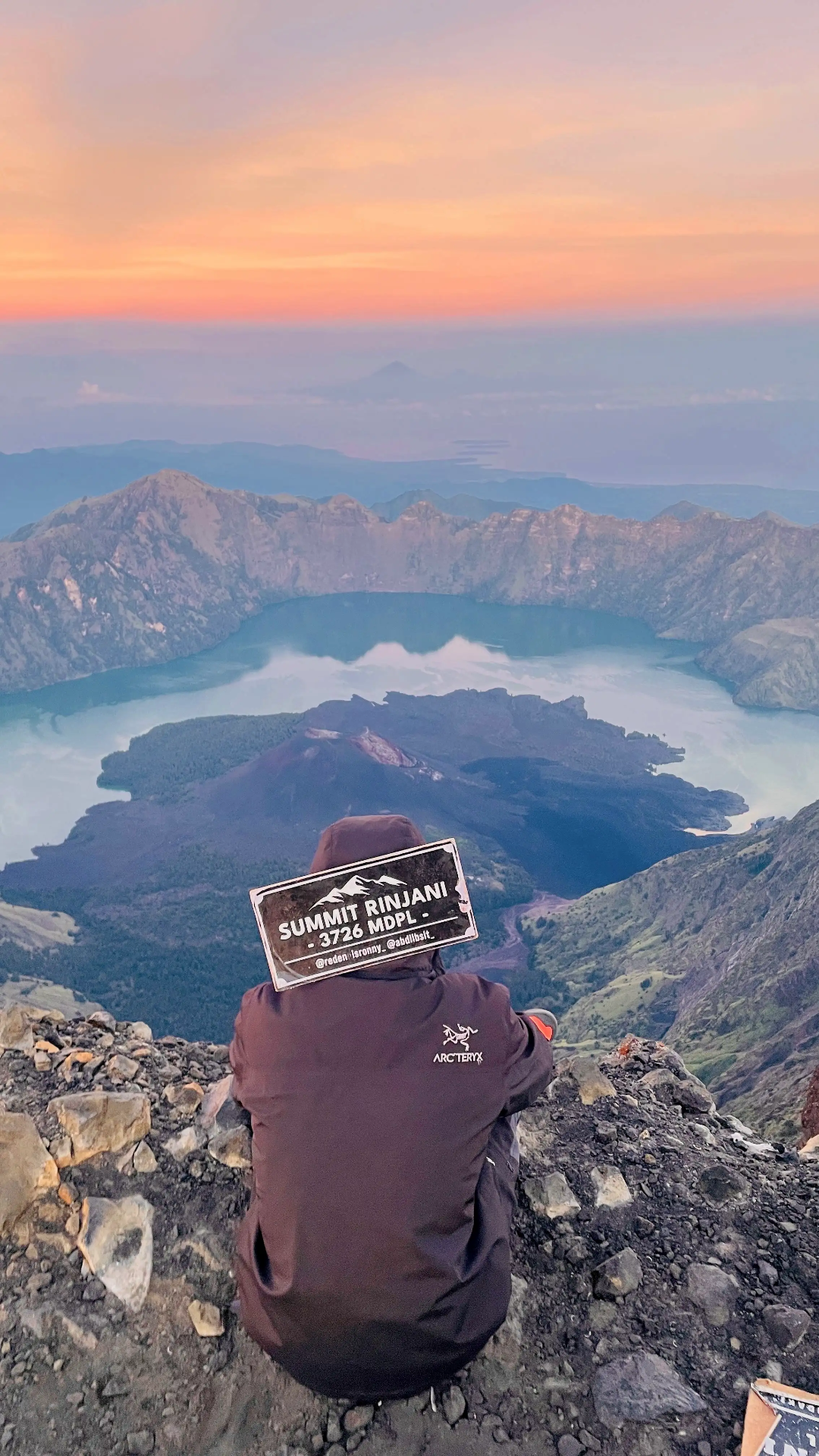 Trekker at Mount Rinjani summit (3,726 m) overlooking Segara Anak crater lake at dawn